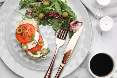Flat lay composition of tasty bruschetta with tomatoes and salad served on white marble tableの写真素材
