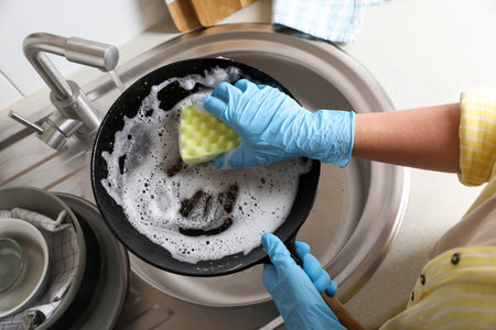 Woman washing dirty frying pan in sink, above viewの写真素材