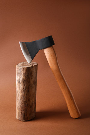 Metal ax in wooden log on brown backgroundの写真素材