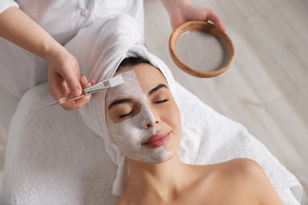 Cosmetologist applying mask on woman's face in spa salon, above viewの写真素材