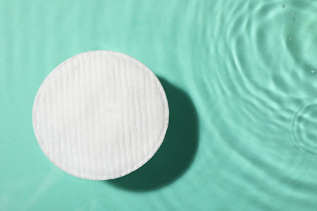 Cotton pad and micellar water on turquoise background, top view. Space for textの写真素材