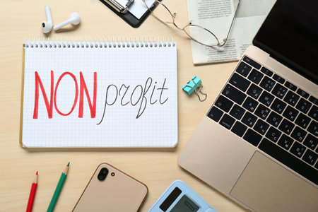 non profit. Flat lay composition with notebook, stationery and laptop on wooden tableの写真素材