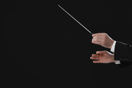 Professional conductor with baton on black background, closeup. Space for textの写真素材