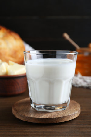 Glass with fresh milk, honey and bread on wooden tableの写真素材