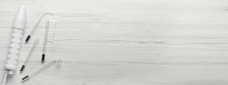 High frequency darsonval device and different nozzles on white wooden background, flat lay. Banner design with space for textの写真素材