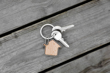 Keys with trinket in shape of house on wooden table, top view. real estate agent servicesの写真素材