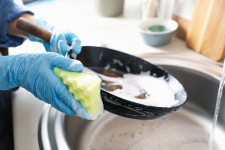 Woman washing dirty frying pan in sink indoors, closeupの写真素材