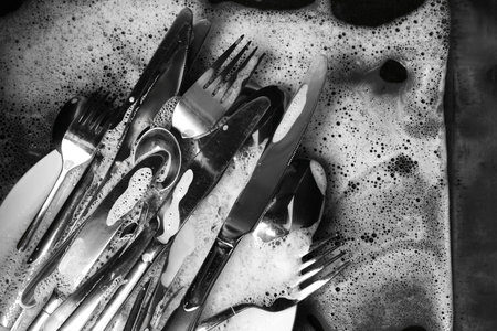 Washing silver spoons, forks and knives in kitchen sink with foam, flat layの写真素材