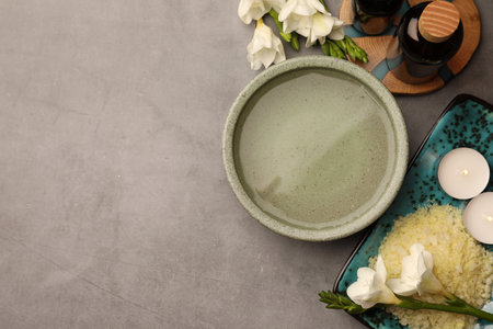 Flat lay composition with essential oil, sea salt and beautiful flowers on gray table, space for text. Aromatherapy treatmentsの写真素材