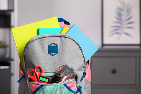 Children's backpack with different school stationery indoors, closeup. Space for textの写真素材