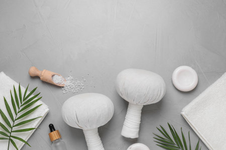 Beautiful spa composition with herbal massage bags and different care products on gray textured table, flat lay. Space for textの写真素材