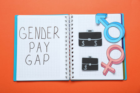 gender pay gap. Notebook, paper briefcases with male and female symbols on orange background, top viewの写真素材