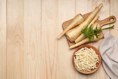 Whole and cut fresh ripe parsnips on wooden table, flat lay. Space for textの写真素材