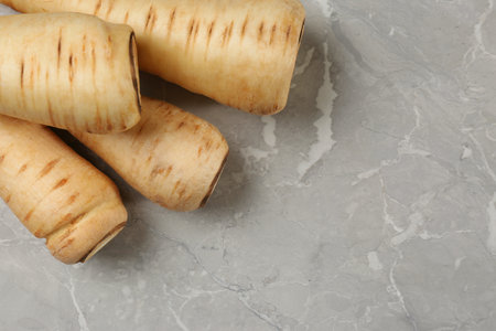 Many fresh ripe parsnips on gray marble table, flat lay. Space for textの写真素材