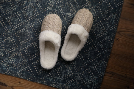 Pair of beautiful soft slippers and rug on wooden floor, top viewの写真素材