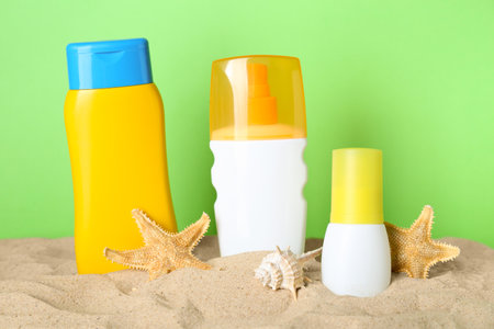 Different suntan products, seashell and starfishes on sand against green backgroundの写真素材