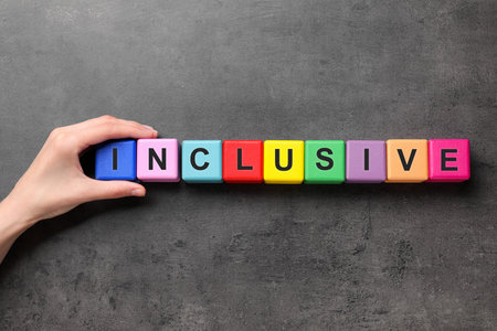 Woman making word Inclusive with cubes on dark gray background, top viewの写真素材
