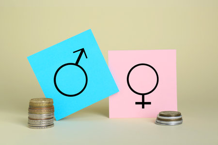 gender pay gap. Male and female symbols near piles of coins on beige backgroundの写真素材