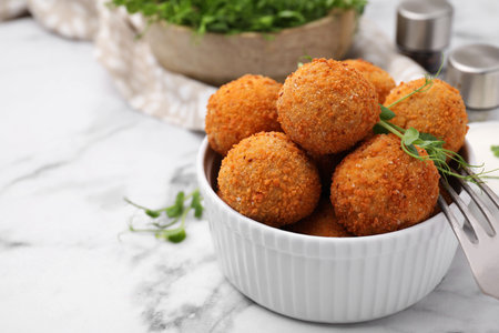 Bowl of delicious fried tofu balls with pea sprouts on white marble table, space for textの写真素材