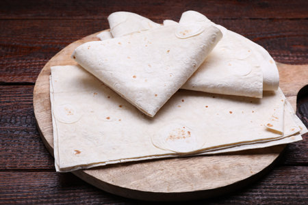 Delicious folded Armenian lavash on wooden table, closeup