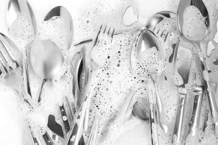 Washing silver spoons, forks and knives in foam, flat layの写真素材