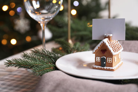 Festive place setting with beautiful dishware and gingerbread house card holder for Christmas dinner on checkered tablecloth, closeup. Space for textの写真素材
