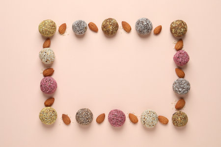 Frame of delicious vegan candy balls and almonds on light background, flat lay. Space for textの写真素材