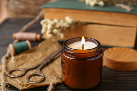 Burning scented candle, book and flowers on wooden table, closeupの写真素材