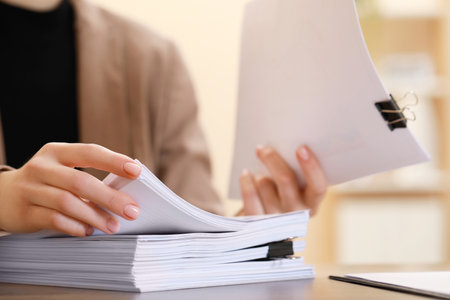 Woman working with documents at table in office, closeup