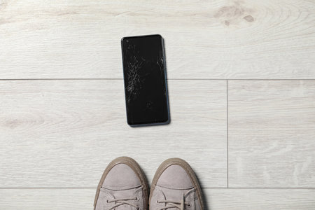 Woman near dropped smartphone on floor, top view. device repairの写真素材