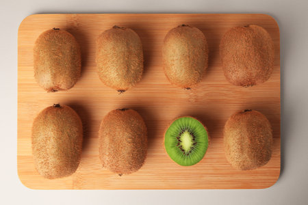 Wooden board with whole kiwis and cut one on beige background, top viewの写真素材