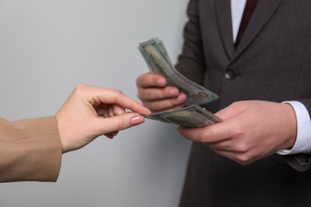 Man giving money to woman on light gray background, closeup. currency exchangeの写真素材