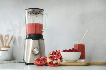 Blender and smoothie ingredients on white table in kitchenの写真素材