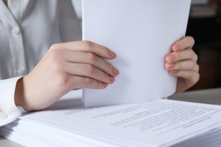 Woman stacking documents at table in office, closeupの写真素材