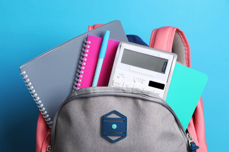 Backpack with different school stationery on light blue backgroundの写真素材