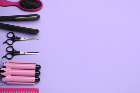 Flat lay composition of professional hairdresser tools on lilac background, space for textの写真素材