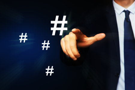 Hashtag concept. Man pointing at sign on dark blue background, closeupの写真素材