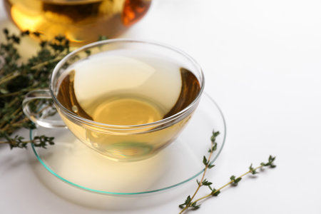 Cup of aromatic herbal tea with thyme on white tableの写真素材