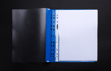 File folder with punched pockets and paper sheets on black background, top viewの写真素材