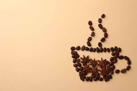 Cup made with coffee beans and anise stars on beige background, flat lay. Space for textの写真素材