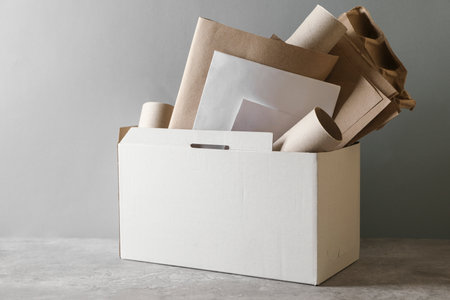 Box with different waste paper on gray table