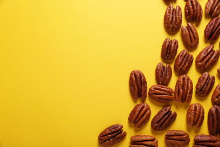 Tasty pecan nuts on yellow background, flat lay. Space for textの写真素材