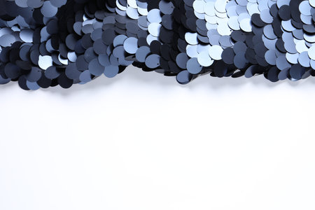 Beautiful shiny sequin fabric on white background, top view. Space for textの写真素材