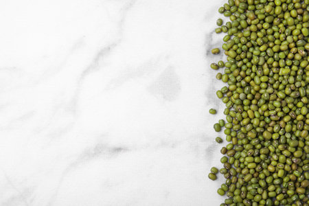 Green mung beans on white marble table, top view. Space for text