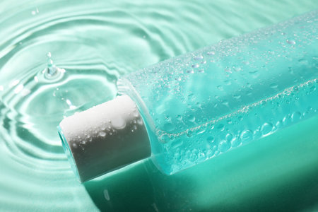 Bottle of micellar water in liquid on turquoise backgroundの写真素材