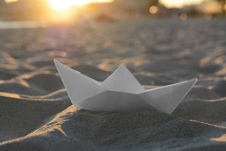 Beautiful white paper boat on sand outdoors, closeupの写真素材