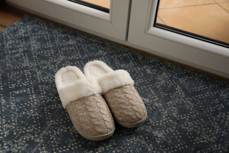 Pair of beautiful soft slippers on mat in roomの写真素材