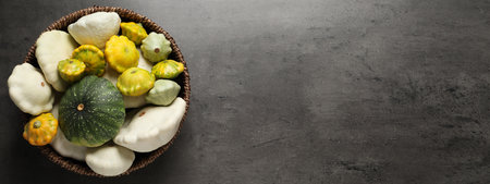 Fresh ripe pattypan squashes in wicker bowl on gray table, top view with space for text. banner...