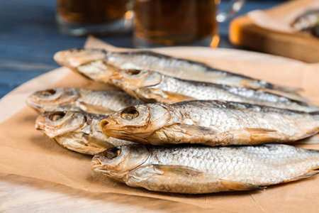 Tasty dried fish on wooden board, closeup