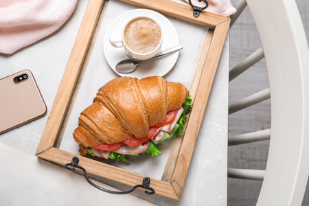 Tasty croissant sandwich and coffee on light gray marble table, flat layの写真素材